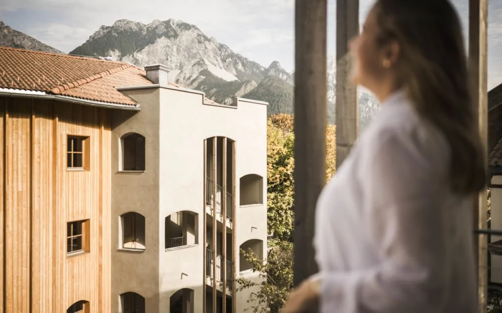 Woman looking from balcony at mountains and buildings in sunlight