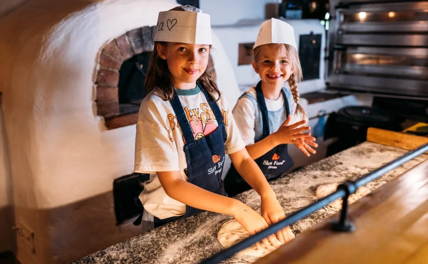 Twee meisjes met kokshelmen kneden deeg in een traditionele bakkerij