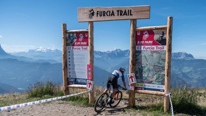 Kronplatz King Marathon – The King of the Dolomites Mountainbiker startet auf dem Furcia Trail mit Berglandschaft im Hintergrund
