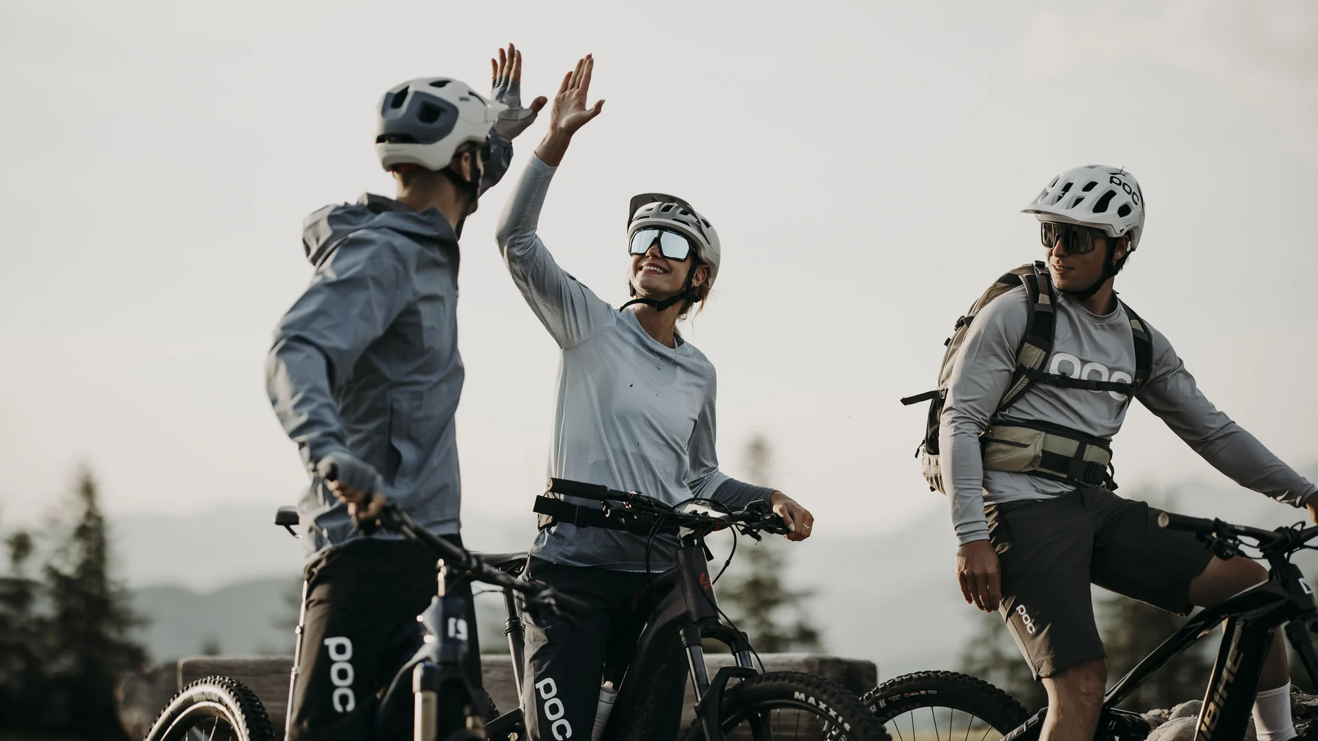 Drei Fahrradfahrer in Helmen geben sich Highfive im Freien