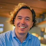 Mann in blauem Hemd lächelt in einem gemütlichen Café