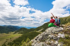 Kinder sitzen auf Felsen und genießen die Berglandschaft bei bewölktem Himmel