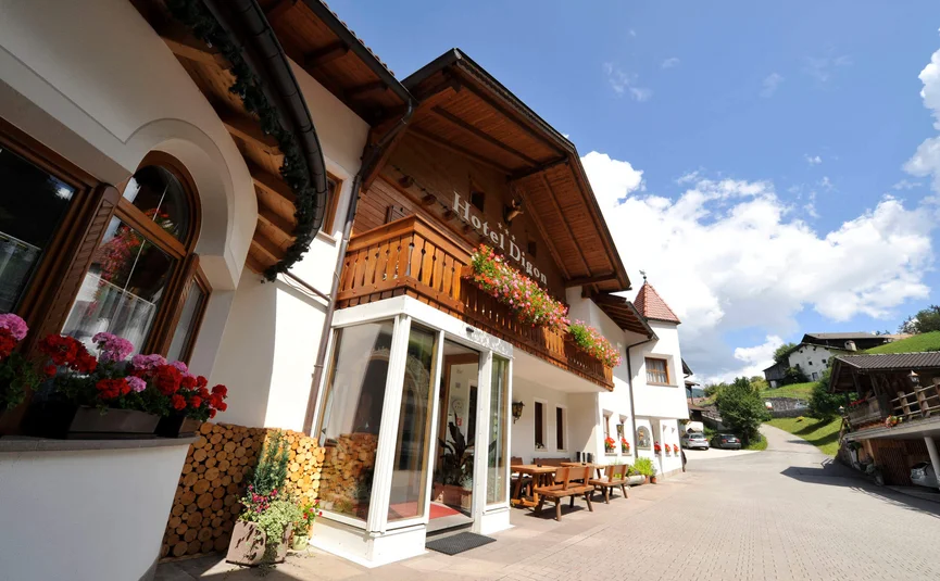 Uitzicht van buiten Hotel Digon met bloemen en zitgedeelte onder blauwe lucht