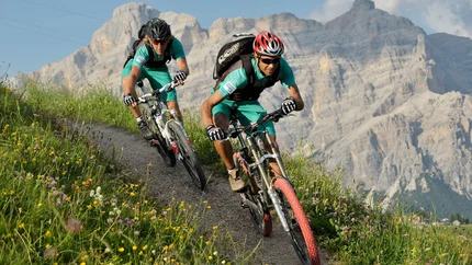 Mountainbike-Urlaub in Alta Badia © Hotel Melodia del Bosco Zwei Mountainbiker fahren auf einem Bergpfad vor Felsen