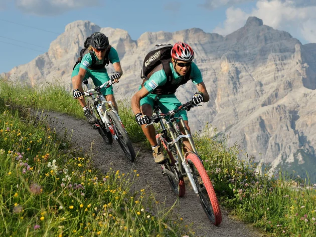 Mountainbike-Urlaub in Alta Badia © Hotel Melodia del Bosco Zwei Mountainbiker fahren auf einem Bergpfad vor Felsen