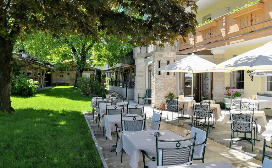 Zonnig terras met gedekte tafels en stoelen naast een gras tuin