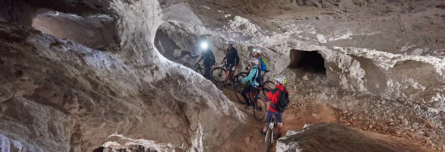 Gruppe von Radfahrern mit Helmen in einer beleuchteten Höhle