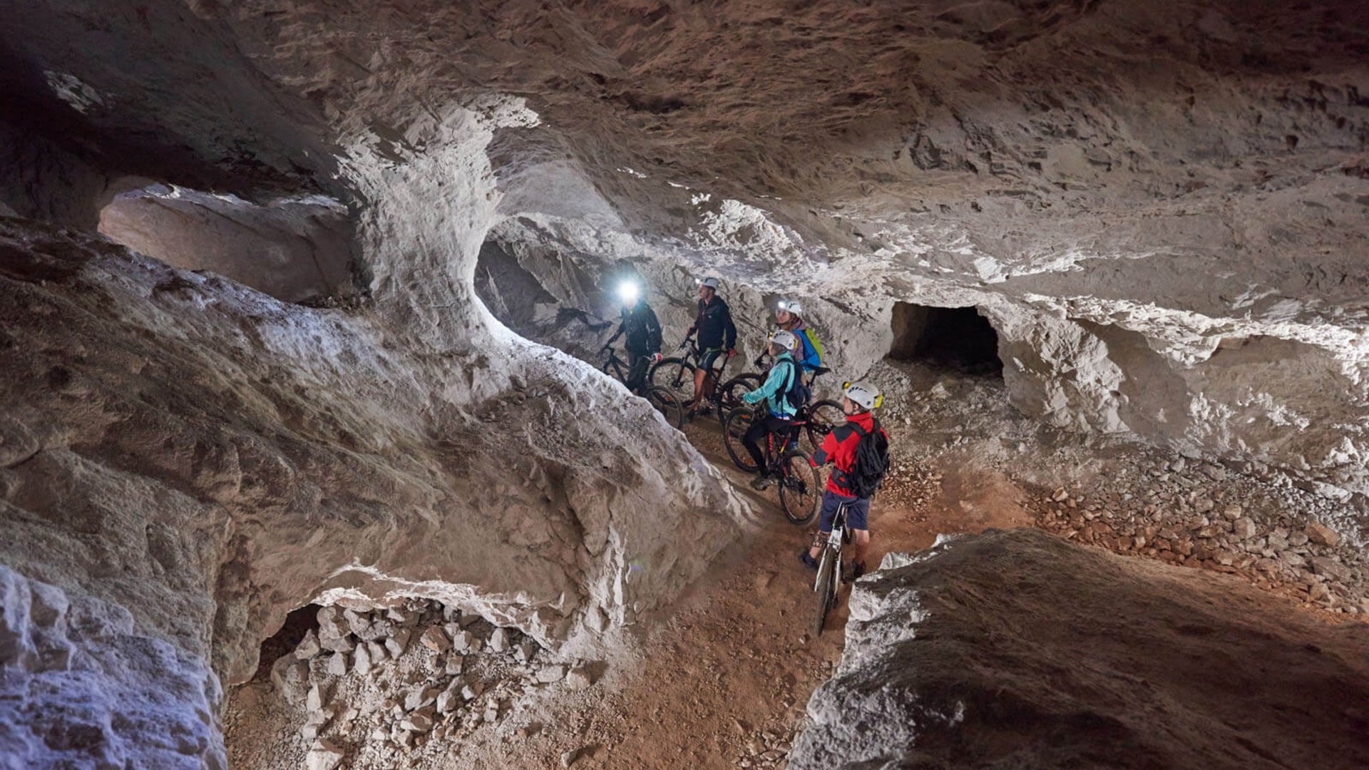 Gruppe von Radfahrern mit Helmen in einer beleuchteten Höhle