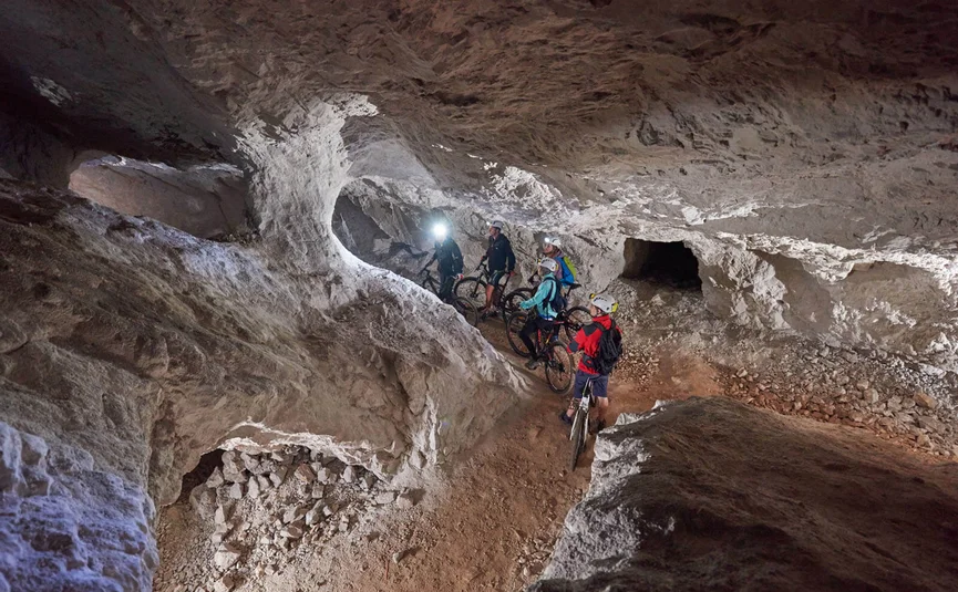 Gruppe von Radfahrern mit Helmen in einer beleuchteten Höhle