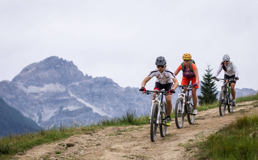 Drie mountainbikers op een pad met bergen op de achtergrond