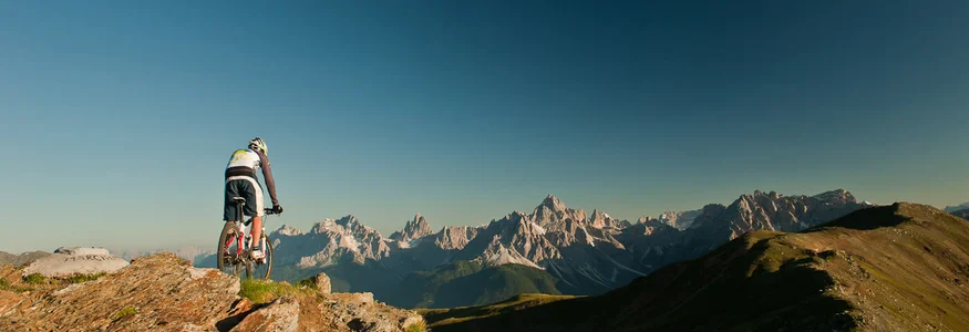 Mountainbiker auf Felsen mit Blick auf Alpen bei klarem Himmel