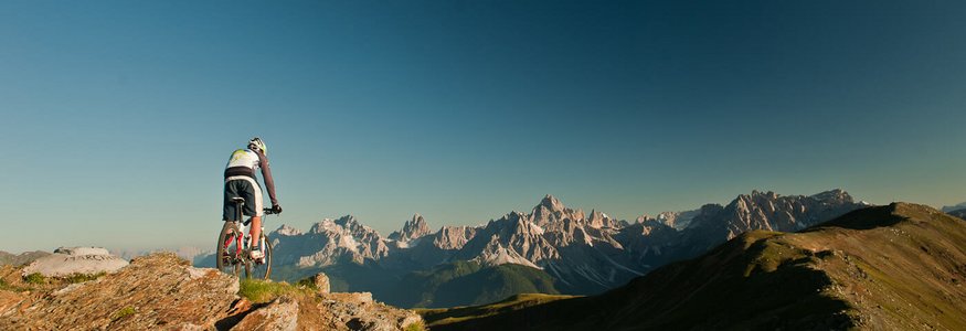 Mountainbiker auf Felsen mit Blick auf Alpen bei klarem Himmel