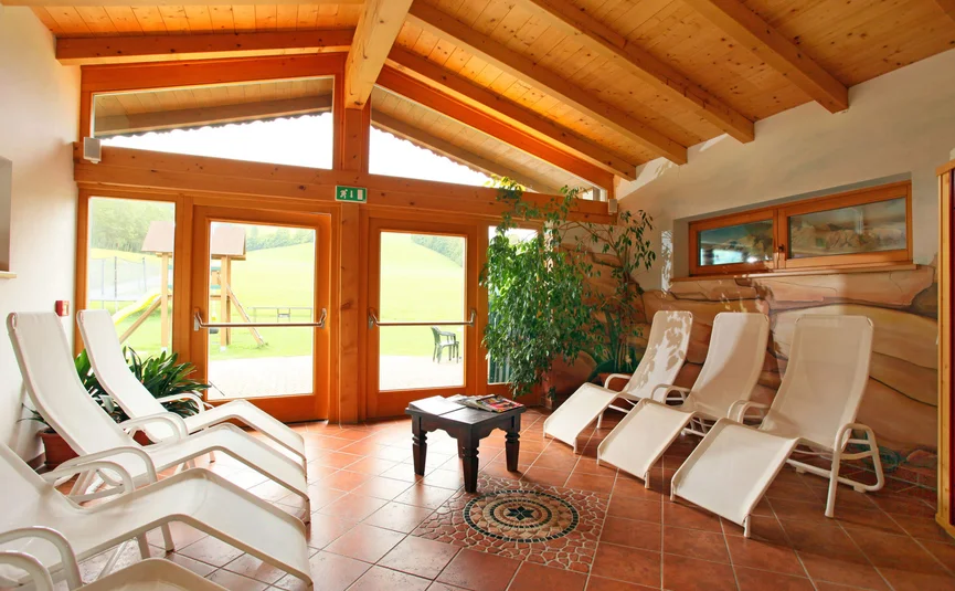 Ruheraum mit Liegestühlen und Holzdach, großer Glastür zum Garten