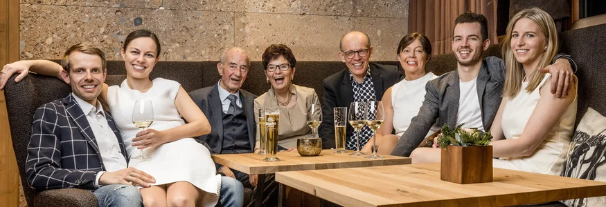 Acht Menschen verschiedenen Alters lachen in einem modernen Wohnzimmer