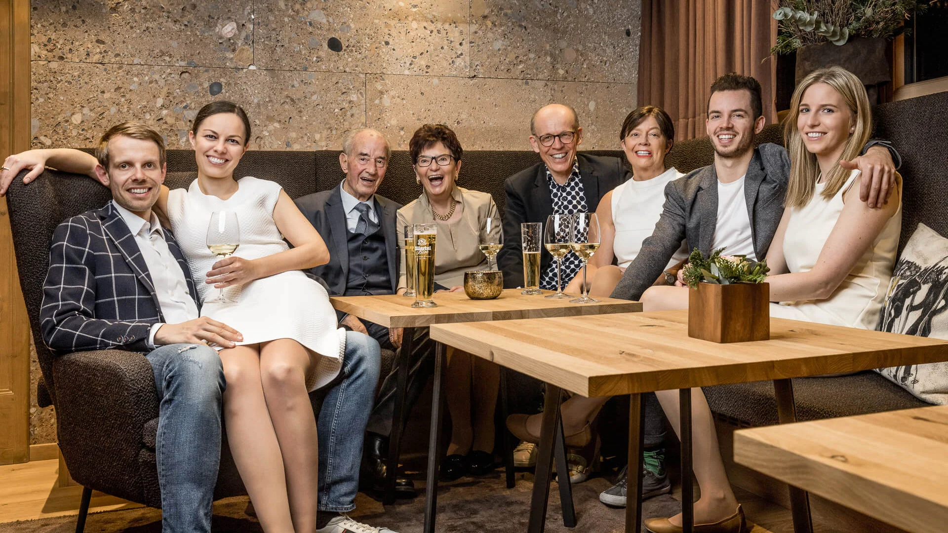Acht Menschen verschiedenen Alters lachen in einem modernen Wohnzimmer