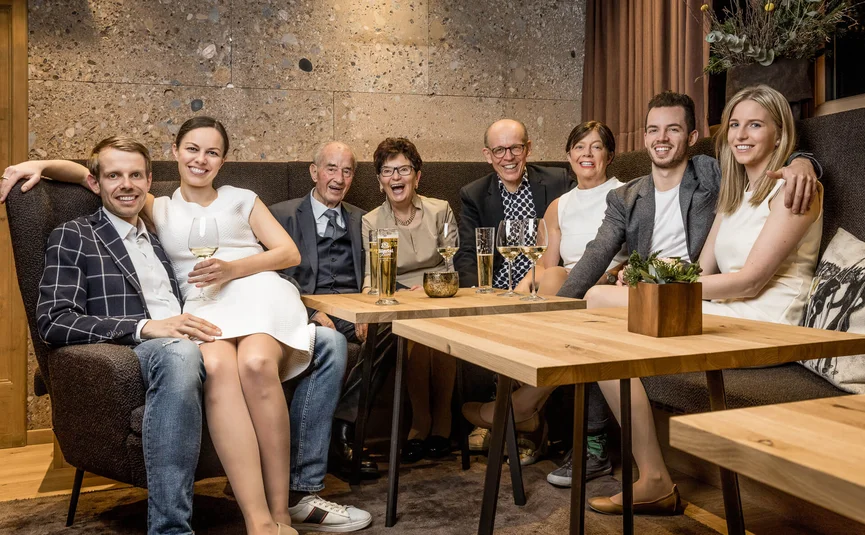 Acht Menschen verschiedenen Alters lachen in einem modernen Wohnzimmer