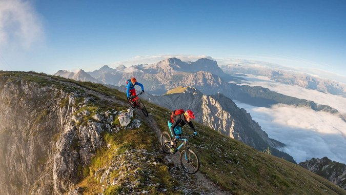 Mountain Bike Holidays © WOM Medien - Andreas Meyer Zwei Mountainbiker auf Bergpfad nahe Gipfelkreuz in den Alpen