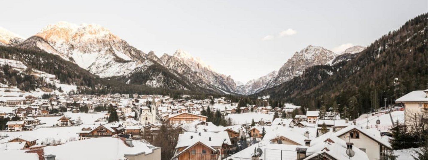 Dolomiti Spring Days S | 4=3 Snow-covered mountain village with pool and mountains in the background