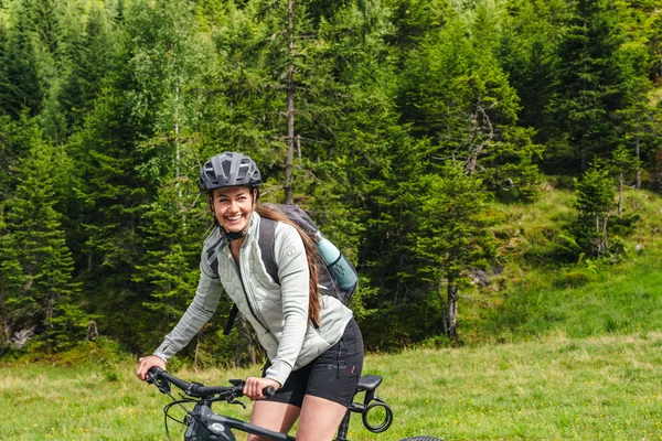 Frau mit Fahrradhelm lächelt beim Mountainbiken im Wald