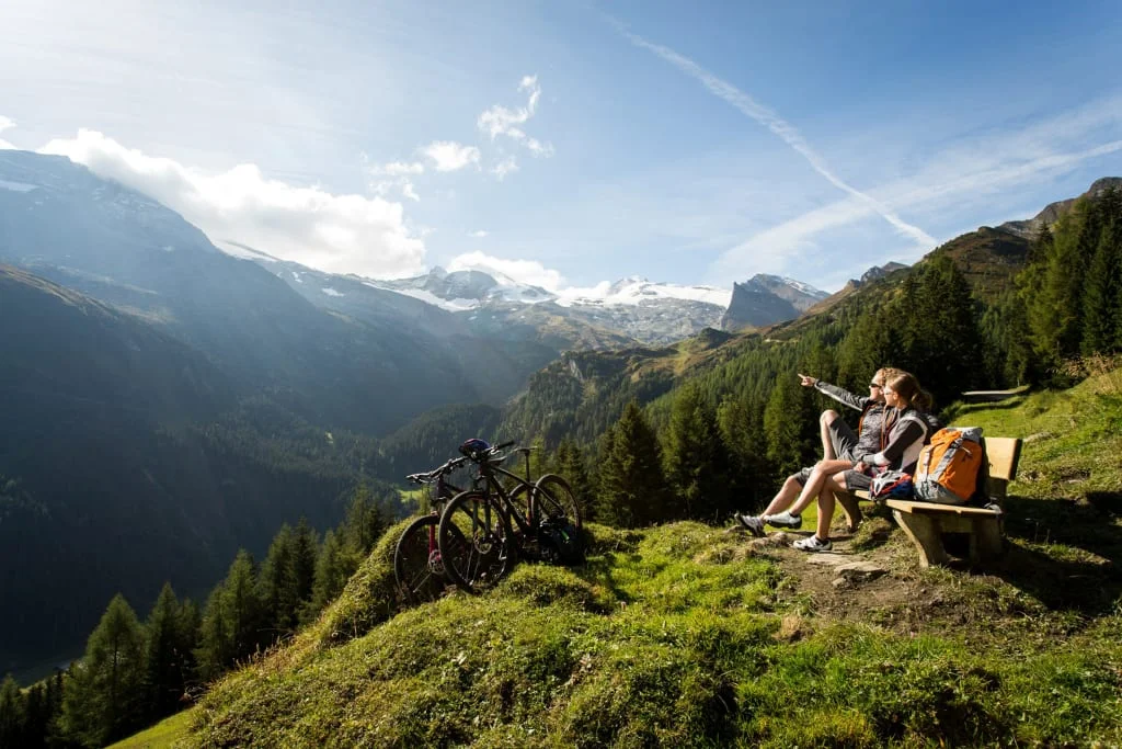 Twee fietsers zitten op een bank en genieten van het bergzicht