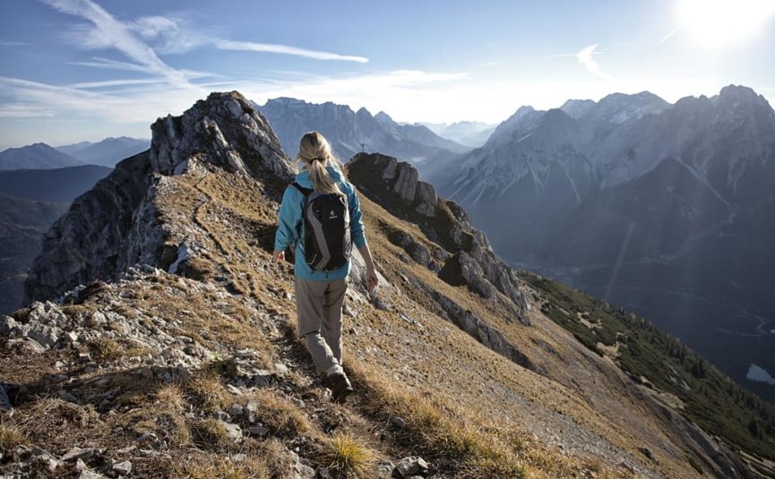Woman hiking on narrow mountain trail with alpine mountain view
