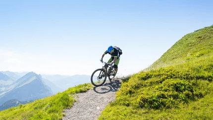Mountainbiker op een steil bergpad met groen gras
