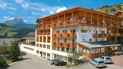 Herberg met rode bloemen en bergen op de achtergrond bij helder weer