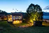 Haus mit beleuchtetem Garten bei Dämmerung in einer ländlichen Umgebung