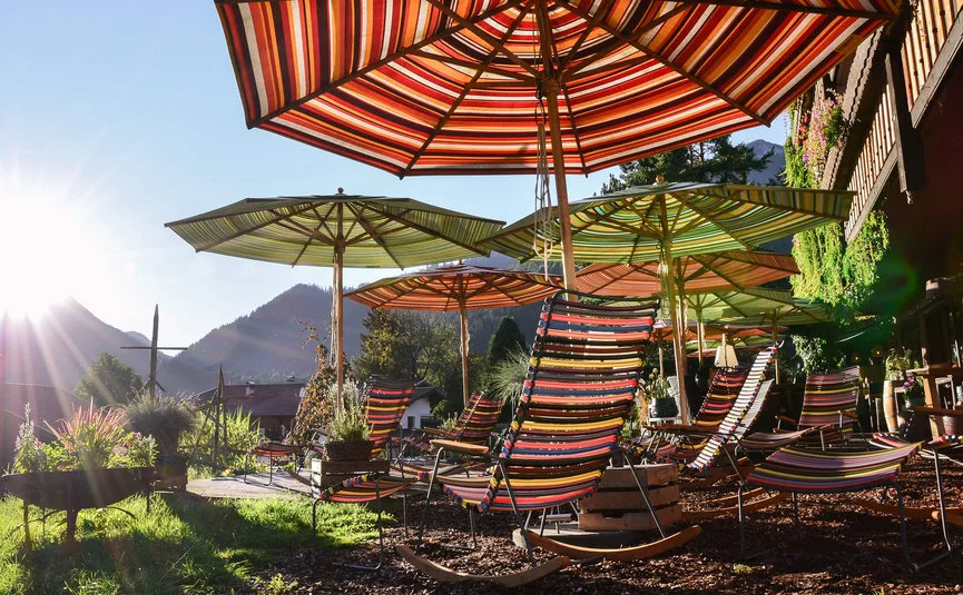 Terrasse mit bunten Liegestühlen und Sonnenschirmen bei Sonnenuntergang