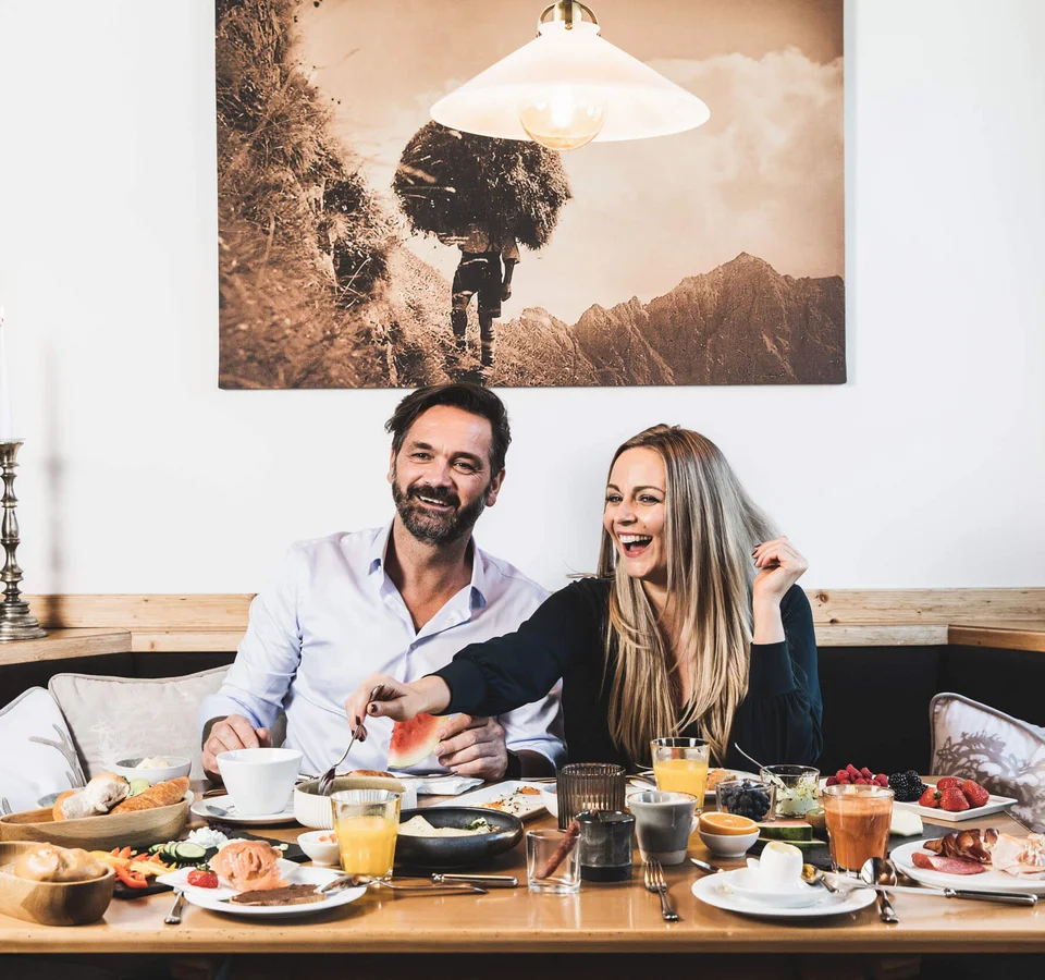 Biken & Genießen im Montanara © Anja Koppitsch Photography Paar genießt Frühstück mit verschiedenen Speisen an einem Holztisch