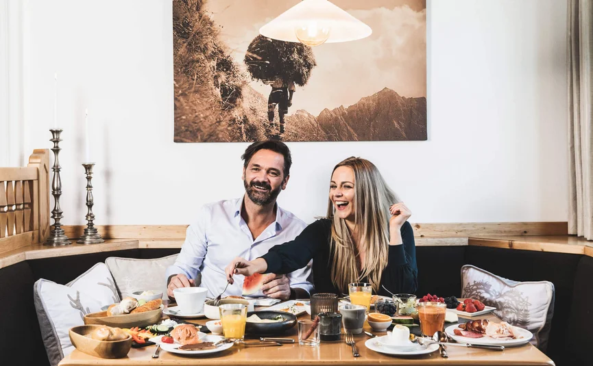 Paar genießt Frühstück mit verschiedenen Speisen an einem Holztisch