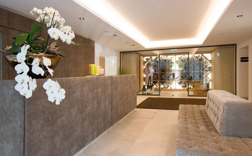 Moderner Wartebereich mit Orchideen, Sitzbank und Weinschrank im Hintergrund