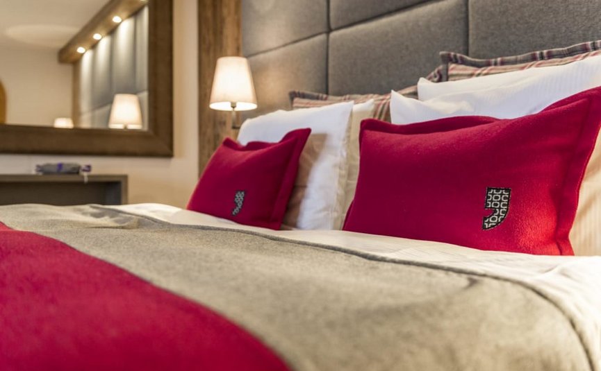 Knus bed met grijs deken en rode kussens in moderne slaapkamer