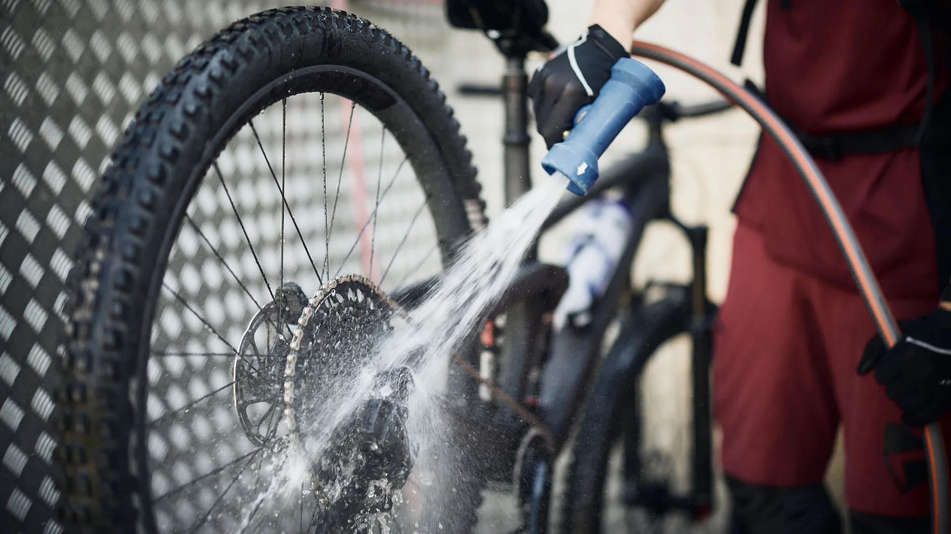 Person reinigt Fahrradkette mit Wasserdusche aus Gartenschlauch