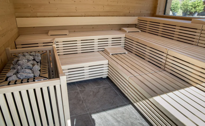 Bright wooden sauna with tiled floor and sauna stove with stones