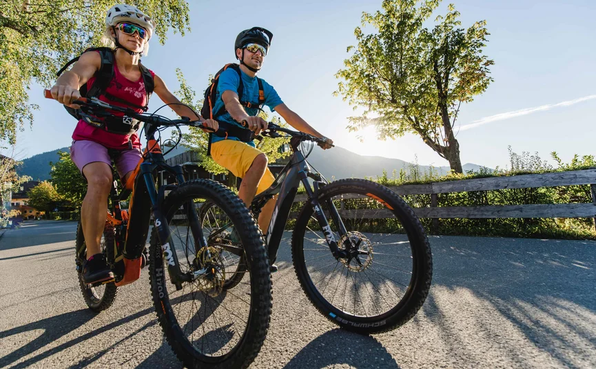 Twee fietsers met helm fietsen op landelijke weg bij zonneschijn