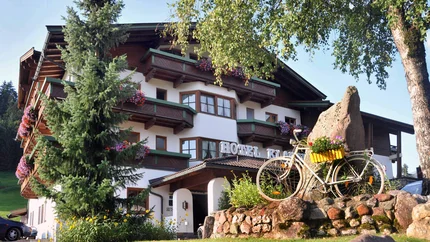 Hotel mit Balkonblumen, Fahrrad und Felsen im Garten