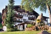 Hotel mit Balkonblumen, Fahrrad und Felsen im Garten