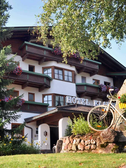 Hotel mit Balkonblumen, Fahrrad und Felsen im Garten