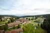 Luftaufnahme eines Ferienresorts in einer grünen, hügeligen Landschaft mit Wald