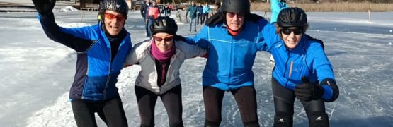 Vier personen die schaatsen op een bevroren meer bij zonnig weer