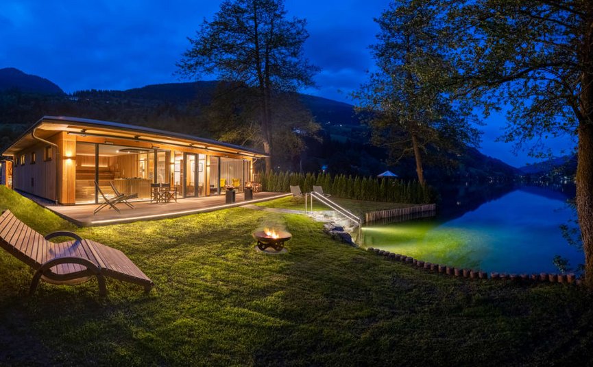 Beleuchtetes Seehaus mit Garten und Feuerstelle in der Nacht