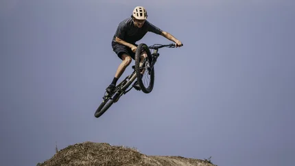 Mountainbiker springt mit seinem Fahrrad über eine Erdhügelbahn