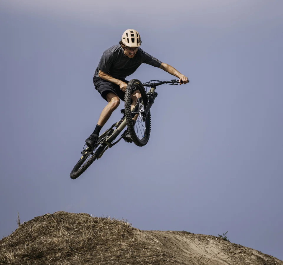 Mountainbiker springt mit seinem Fahrrad über eine Erdhügelbahn