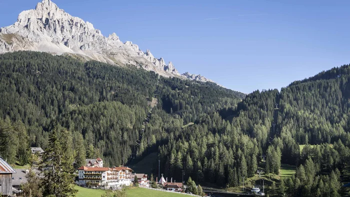 Berglandschaft mit Wald, Häusern und Sessellift bei klarem Himmel