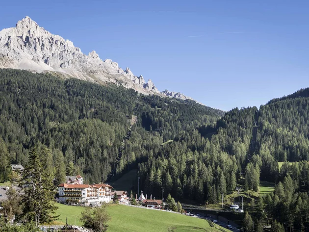 Mountain landscape with forest, houses, and chairlift under clear sky