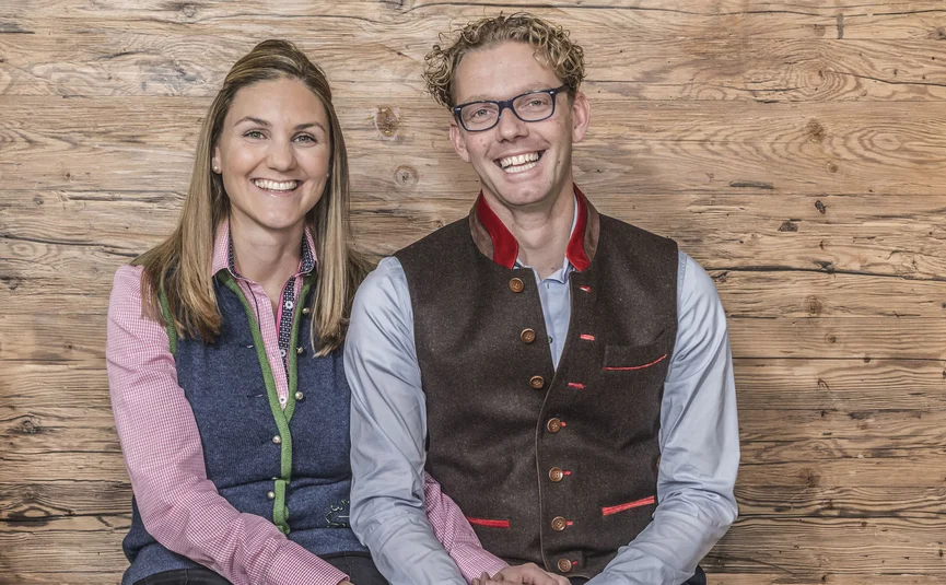 Fröhliches Paar sitzt vor Holzwand und hält Hände