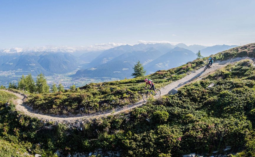 Mountainbikers rijden op een bergpad met Alpenlandschap bij zonnig weer