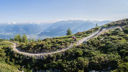 Mountainbikers rijden op een bergpad met Alpenlandschap bij zonnig weer