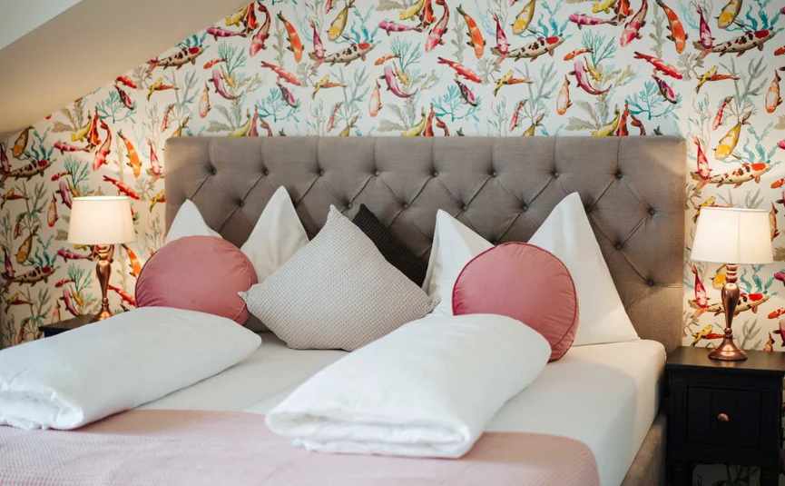 Cozy bed with colorful fish wallpaper and pillows in bedroom